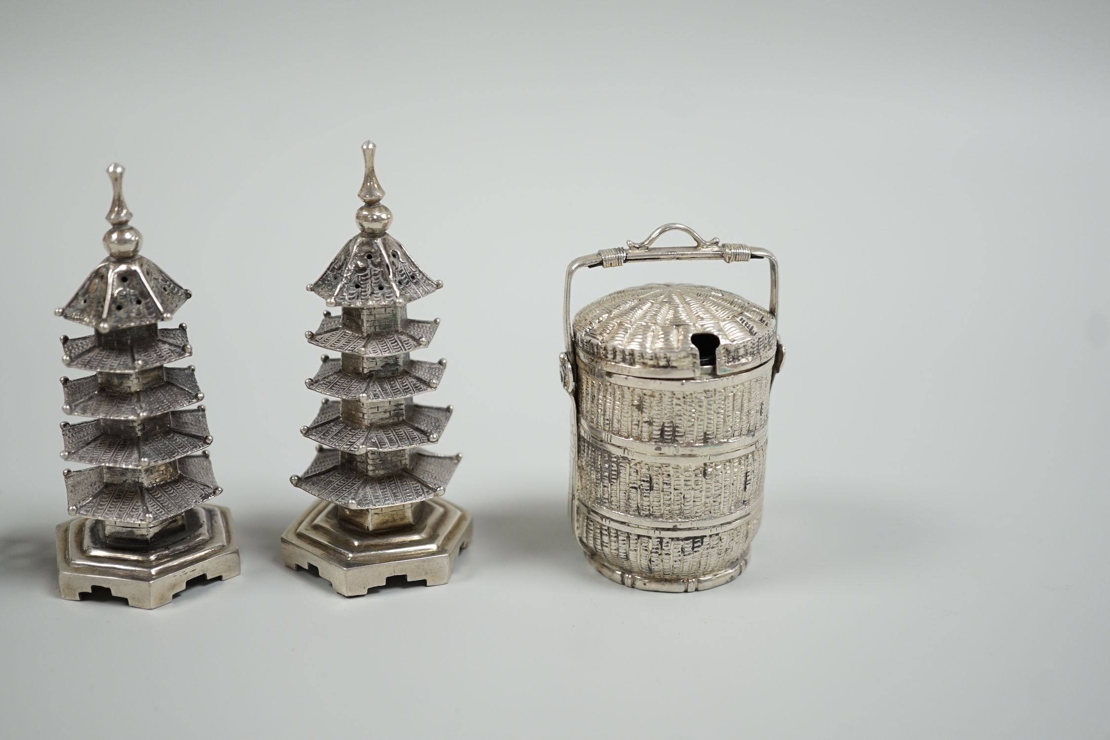 A Chinese white metal 'wedding basket' by Wang Hing, 63mm, a pair of similar white metal pagoda condiments, KSM and a figure.